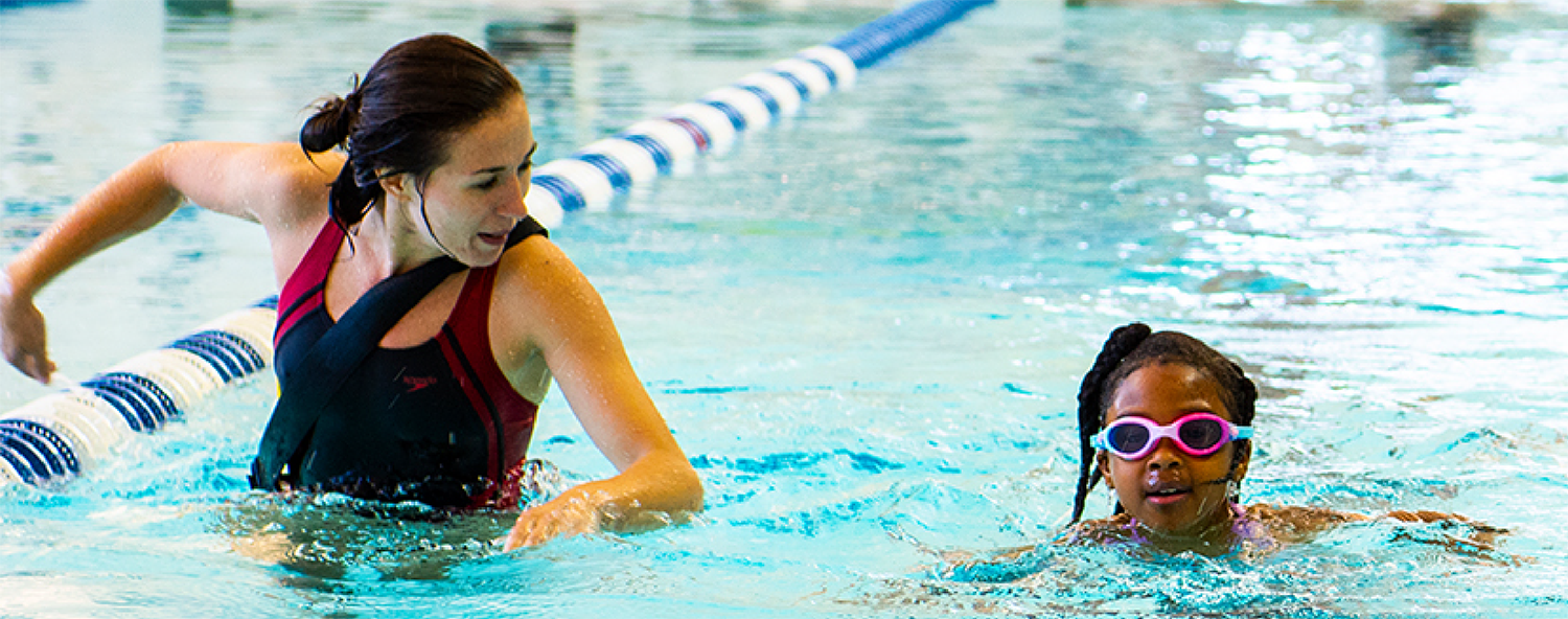 A woman at the CRC pool giving swimming lessons to a child.