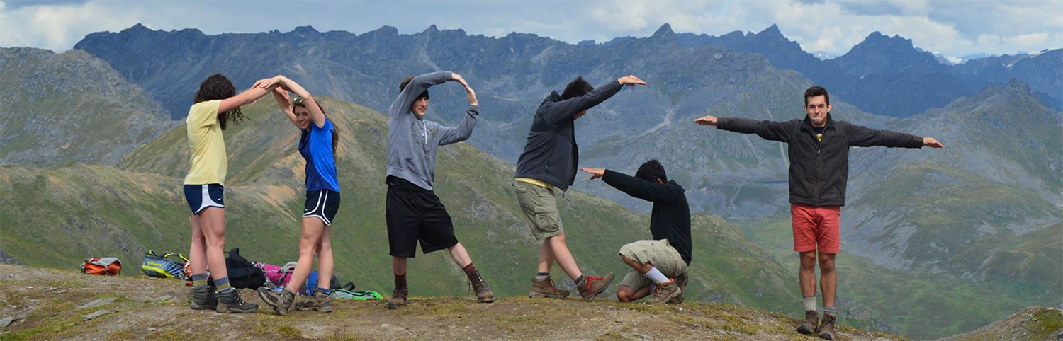Six young men and women creating the ORGT letters with their bodies on top of a mountain.