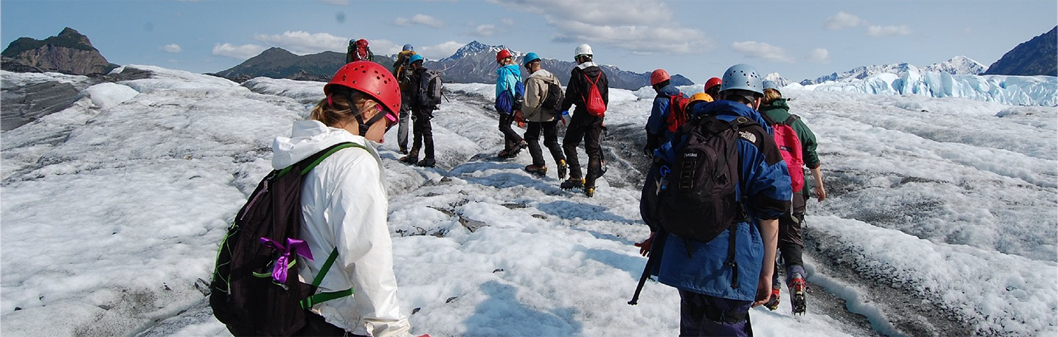 A group of people walking up a snowy mountain.