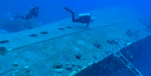 scuba divers above ship wreck